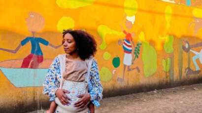 a woman with a baby in Cabo Verde in front of street art